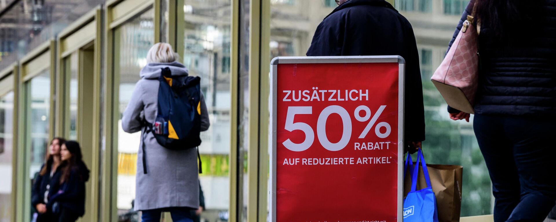 Pessoas passam por uma placa que anuncia um desconto extra de 50% em itens já com desconto do lado de fora de uma loja de varejo de roupas em Berlim, 29 de setembro de 2022 - Sputnik Brasil, 1920, 31.10.2022