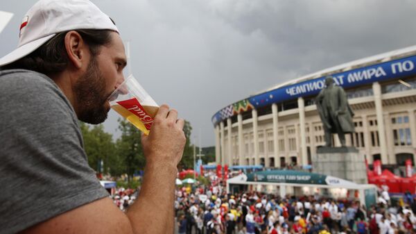 Homem bebe cerveja em pavilhão da Budweiser em frente a estátua de Lenin e ao estádio Luzhniki, durante a Copa do Mundo de 2018, em Moscou, na Rússia - Sputnik Brasil