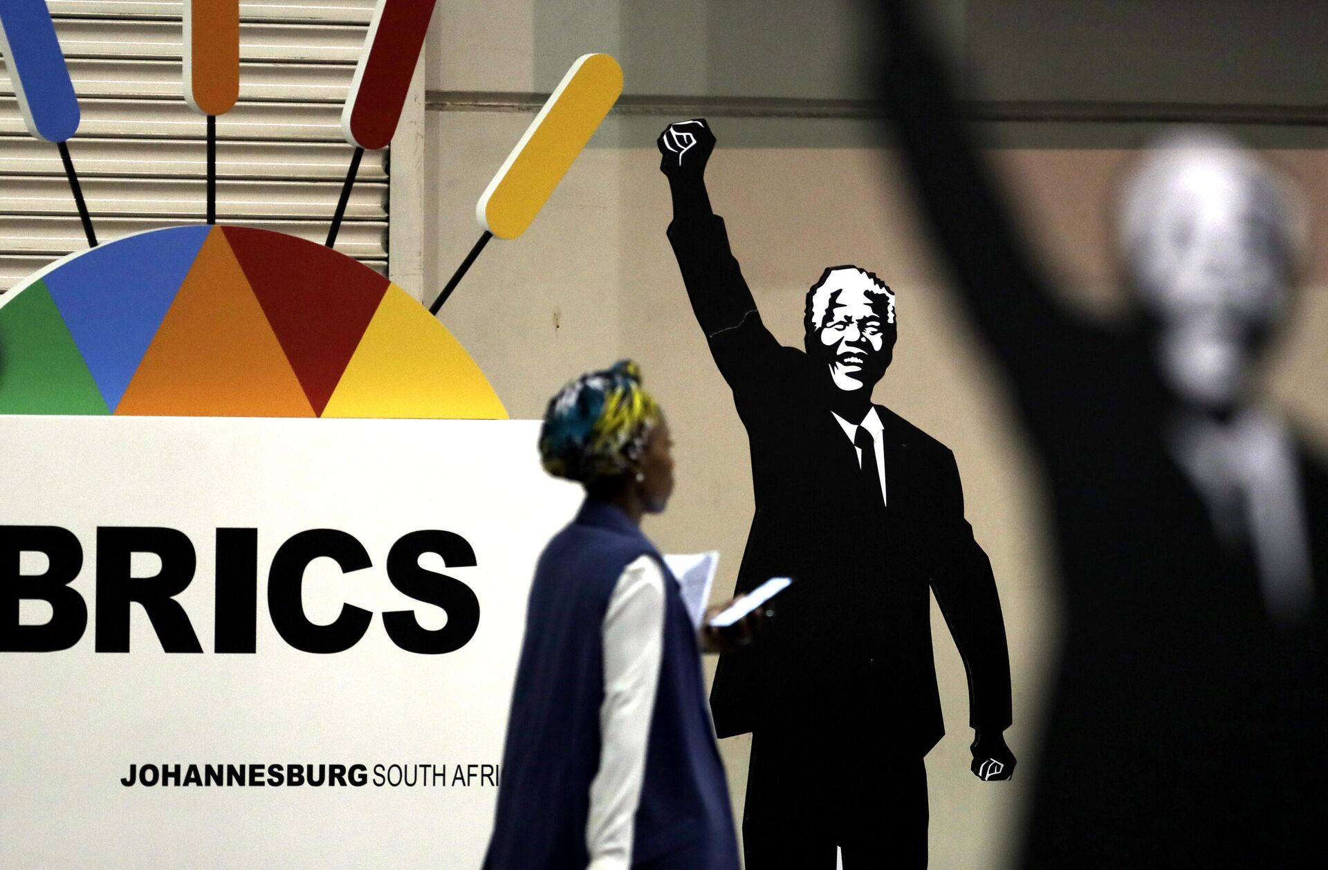 Mulher passa diante de cartaz em homenagem ao ex-presidente da África do Sul Nelson Mandela durante encontro do BRICS em Joanesburgo, na África do Sul, em 27 de julho de 2018 - Sputnik Brasil, 1920, 22.02.2023