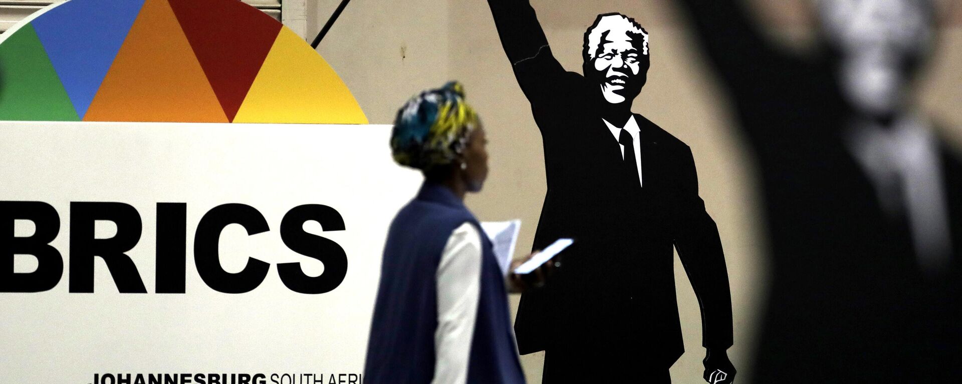 Mulher passa diante de cartaz em homenagem ao ex-presidente da África do Sul Nelson Mandela durante encontro do BRICS em Joanesburgo, na África do Sul, em 27 de julho de 2018 - Sputnik Brasil, 1920, 26.04.2023