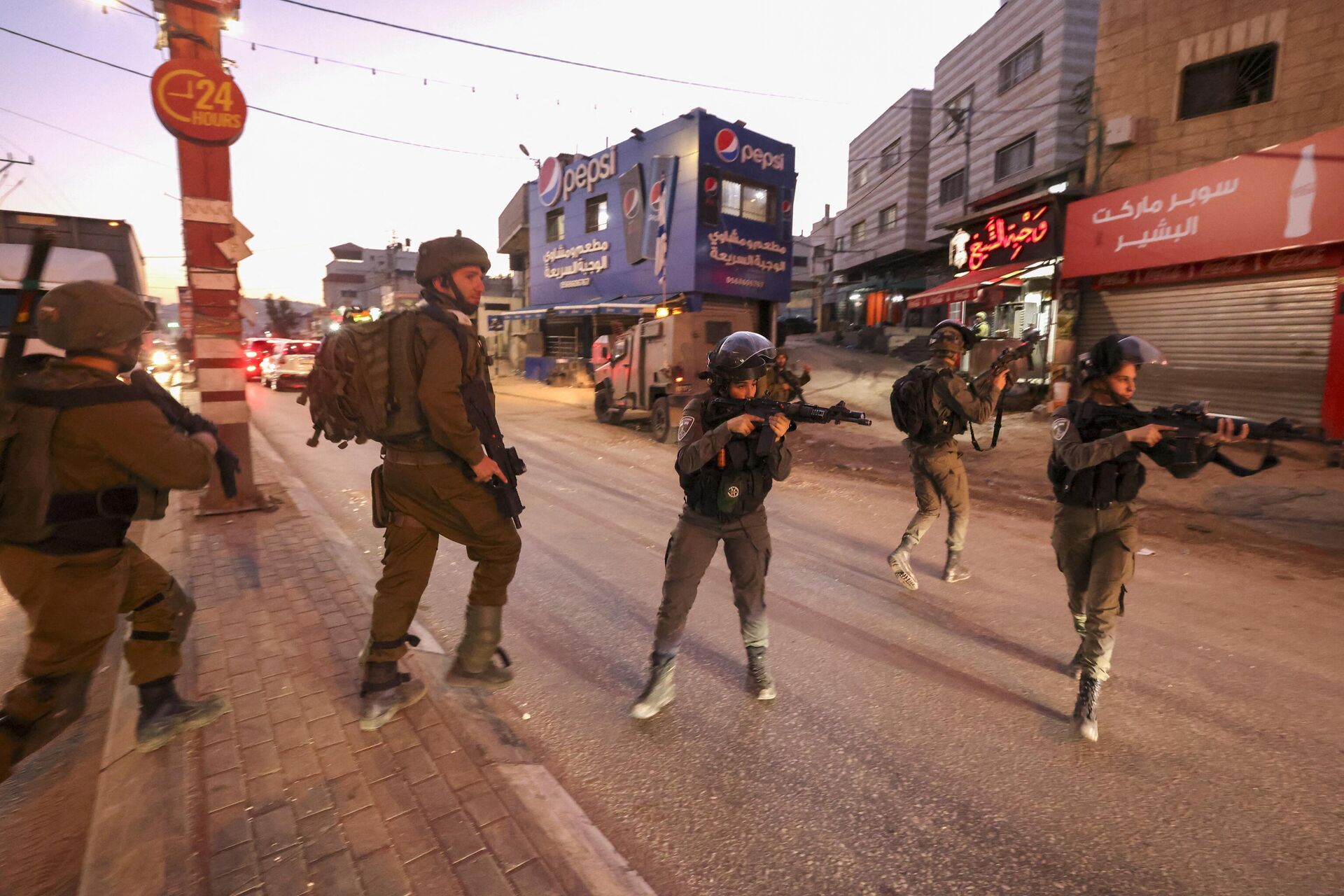 As forças de segurança israelenses apontam suas armas enquanto se posicionam na cidade ocupada de Hawara, na Cisjordânia, após um incidente durante o qual um palestino foi morto a tiros pela polícia israelense, em 2 de dezembro de 2022 - Sputnik Brasil, 1920, 06.12.2022