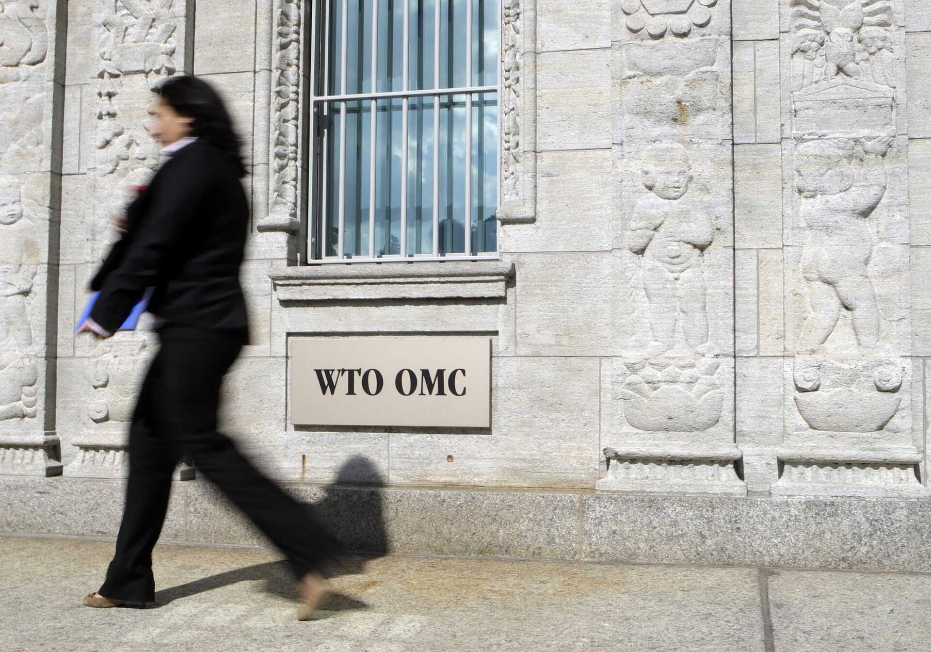 Pessoa caminha em frente à entrada do prédio da Organização Mundial do Comércio (OMC) em Genebra, Suíça, sexta-feira, 22 de junho de 2007 - Sputnik Brasil, 1920, 21.09.2023