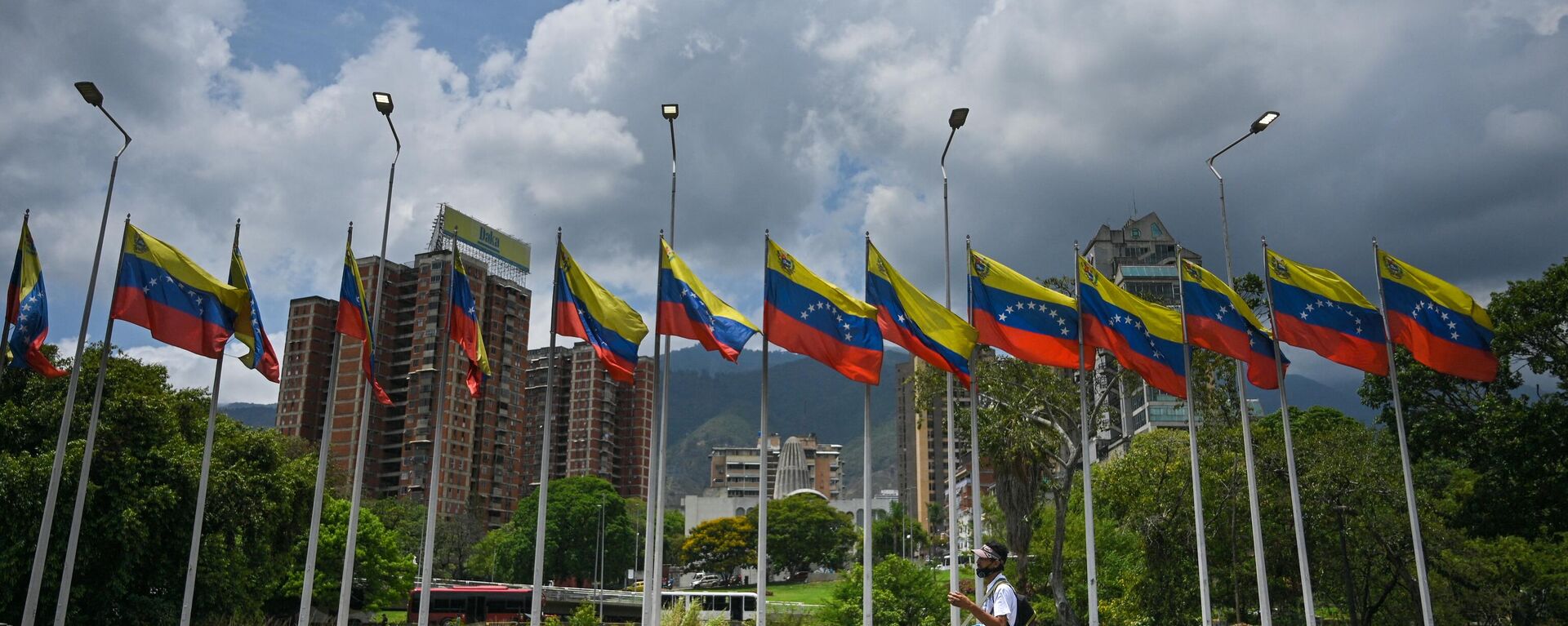 Pessoa passa ao lado de uma série de bandeiras venezuelanas em uma rodovia em Caracas, Venezuela, 22 de abril de 2022 - Sputnik Brasil, 1920, 18.12.2022