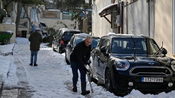Um homem remexe a neve em uma rua em Atenas após uma tempestade de neve que interrompeu o tráfego na capital grega, 25 de janeiro de 2022 - Sputnik Brasil