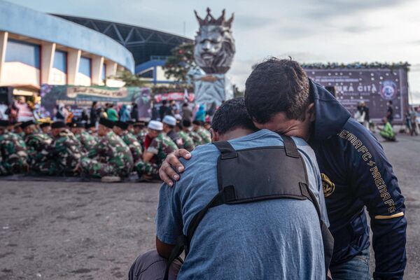 Soldados do Exército indonésio e civis prestam homenagem às vítimas do pisoteio no estádio Kanjuruhan em Malang, na ilha indonésia de Java Oriental, em 4 de outubro de 2022. Pelo menos, 130 morreram no incidente, segundo mais mortal na história do futebol. - Sputnik Brasil