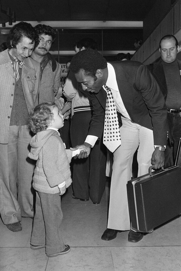 Pelé cumprimenta uma criança, em 12 de setembro de 1976, ao chegar ao aeroporto de Orly, com sua equipe New York Cosmos, para assistir a um amistoso contra o Paris Saint-Germain, em 15 de setembro de 1976. - Sputnik Brasil