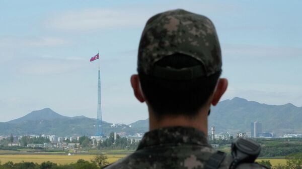 Uma bandeira norte-coreana tremula ao vento enquanto um soldado do exército sul-coreano monta guarda nas aldeias fronteiriças de Panmunjom em Paju, Coreia do Sul, 4 de outubro de 2022 - Sputnik Brasil