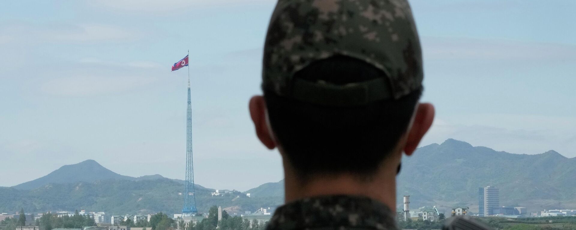 Uma bandeira norte-coreana tremula ao vento enquanto um soldado do exército sul-coreano monta guarda nas aldeias fronteiriças de Panmunjom em Paju, Coreia do Sul, 4 de outubro de 2022 - Sputnik Brasil, 1920, 01.01.2023