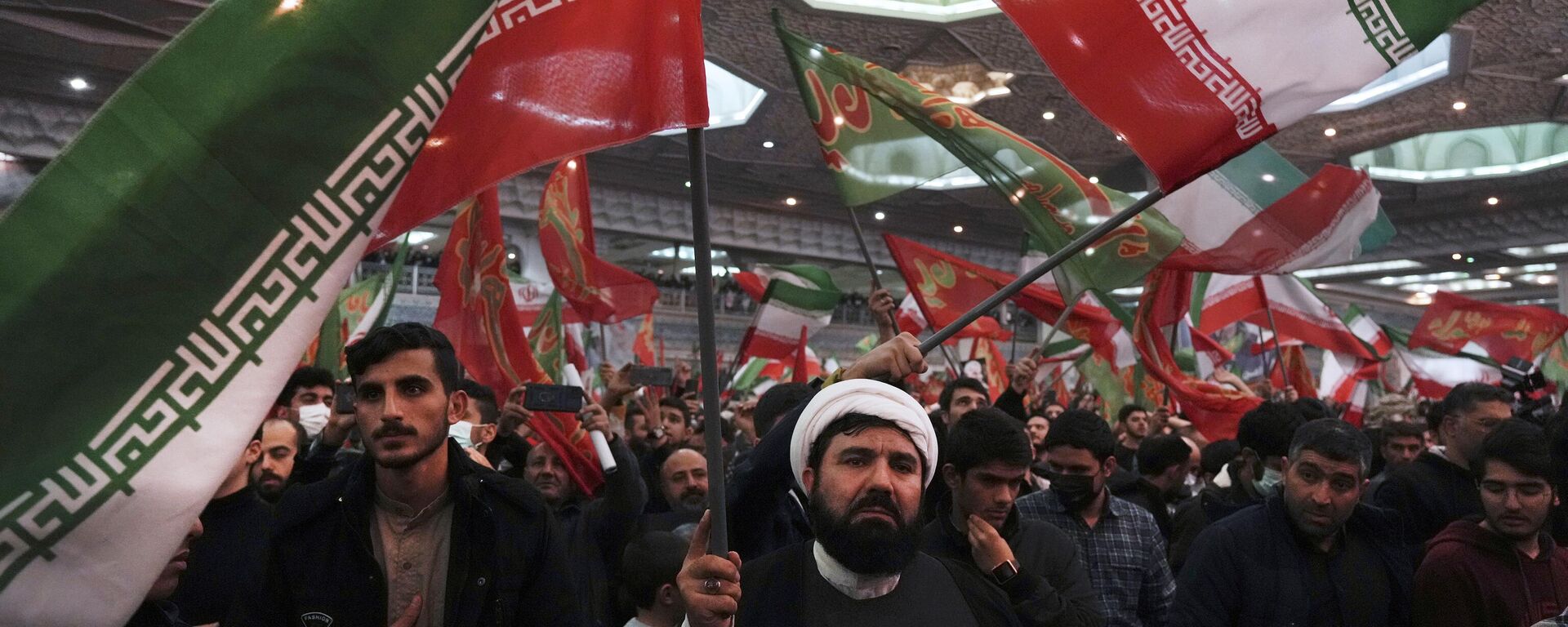 Enlutados agitam bandeiras iranianas e islâmicas durante uma cerimônia que marca o aniversário da morte do general da Guarda Revolucionária Qassem Soleimani na Grande Mesquita Imam Khomeini em Teerã, Irã, 3 de janeiro 2023 - Sputnik Brasil, 1920, 03.01.2023
