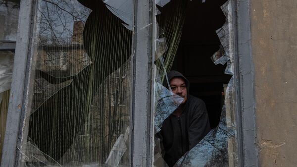 Morador olha pela janela quebrada de uma casa em Donetsk após bombardeio em 4 de janeiro de 2023 - Sputnik Brasil