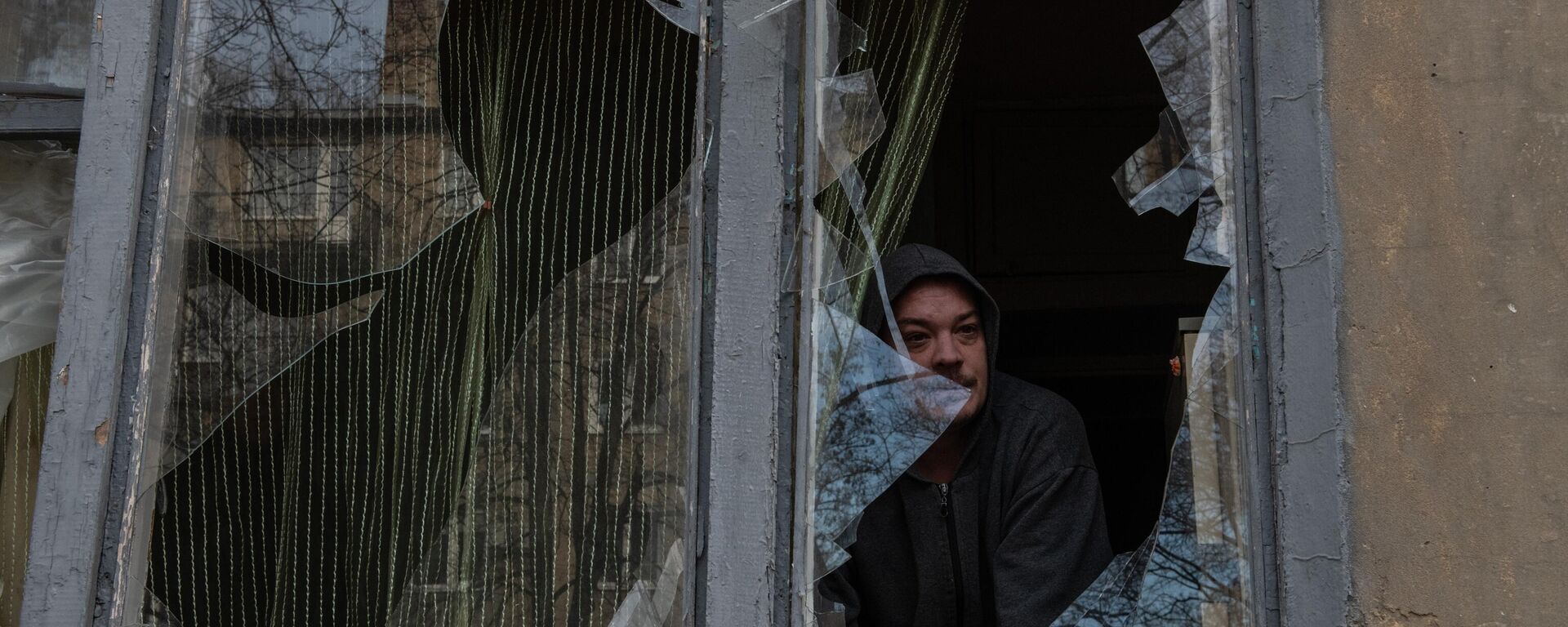 Morador olha pela janela quebrada de uma casa em Donetsk após bombardeio em 4 de janeiro de 2023 - Sputnik Brasil, 1920, 16.02.2023