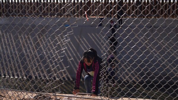 Migrantes entram ilegalmente nos Estados Unidos vindos do México por meio de um buraco aberto na cerca da fronteira em El Paso, Texas, EUA, 21 de dezembro de 2022  - Sputnik Brasil