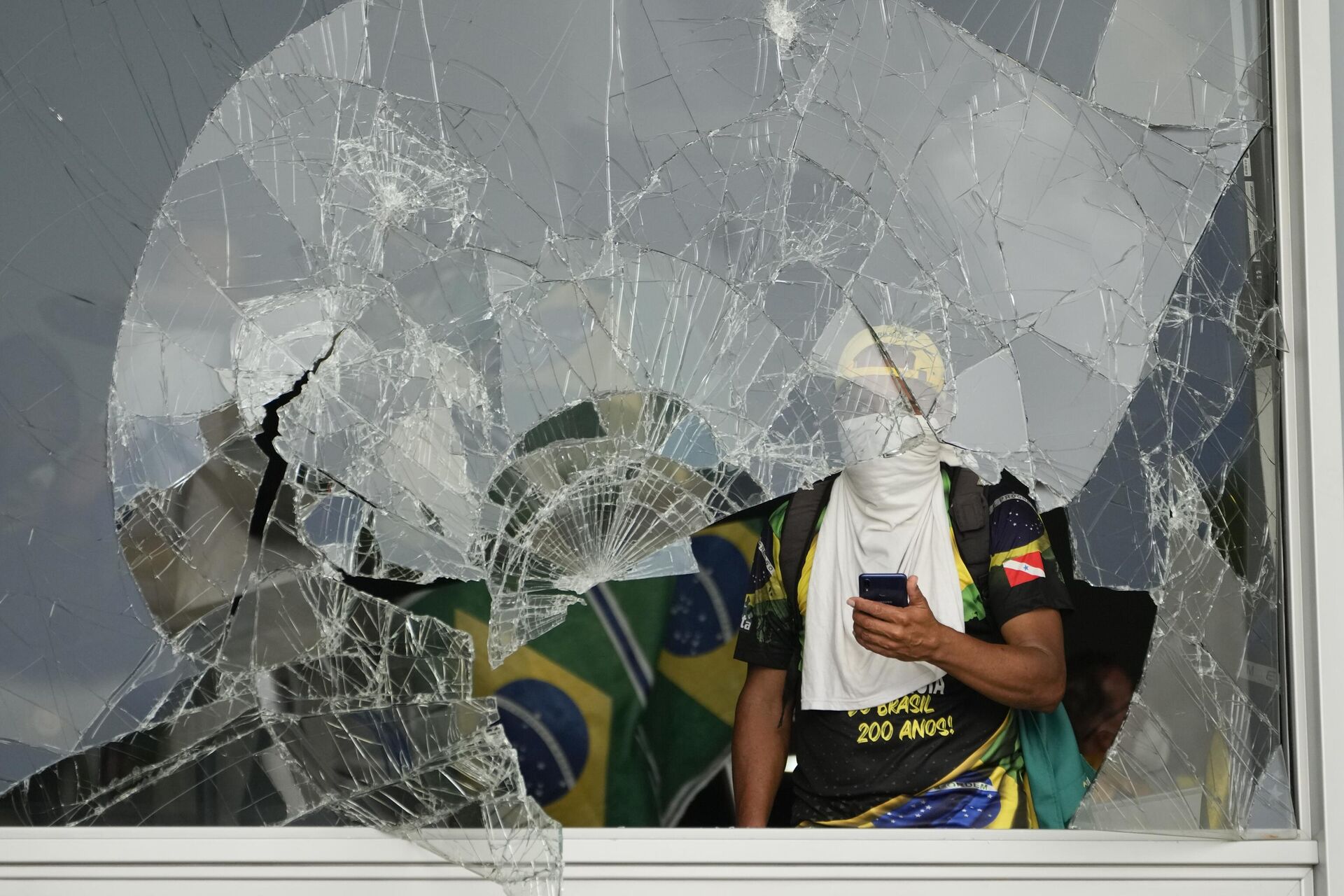Manifestantes bolsonaristas detrás de janela destruída após invasão do Palácio do Planalto. Brasília (DF), 8 de janeiro de 2023 - Sputnik Brasil, 1920, 08.01.2023