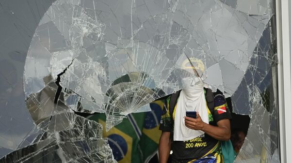 Manifestantes bolsonaristas por trás de janela destruída após invasão no Palácio do Planalto. Brasília (DF), 8 de janeiro de 2023 - Sputnik Brasil