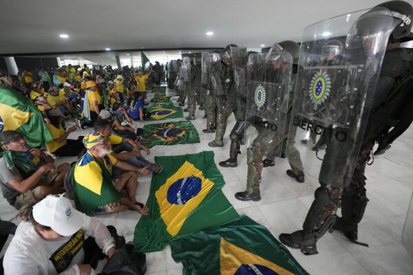Manifestantes bolsonaristas sentam em frente a agentes do Exército no Palácio do Planalto em meio à invasão de prédios públicos na capital brasileira, Brasília, 8 de janeiro de 2023 - Sputnik Brasil