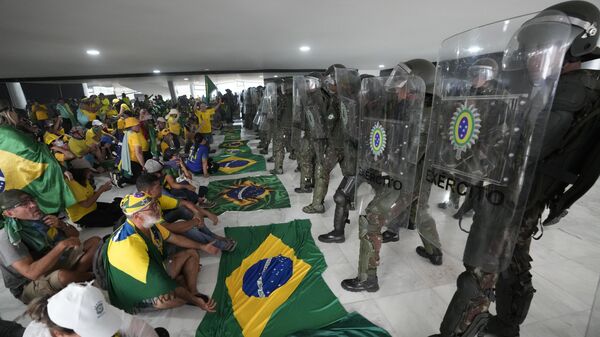 Manifestantes bolsonaristas sentam em frente a agentes do Exército no Palácio do Planalto em meio à invasão de prédios públicos na capital brasileira. Brasília, Distrito Federal, 8 de janeiro de 2023 - Sputnik Brasil