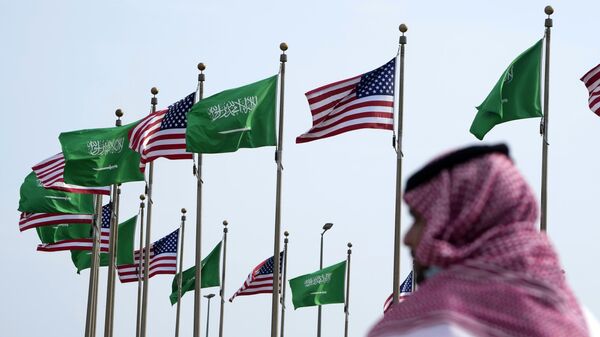 Homem caminha próximo das bandeiras da Arábia Saudita e dos EUA - Sputnik Brasil