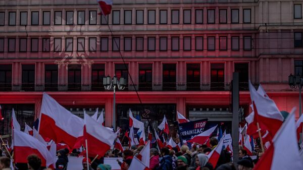 A águia polonesa é projetada na fachada de um prédio enquanto participantes com bandeiras polonesas participam da marcha do Dia da Independência do país organizada em Varsóvia em 11 de novembro de 2022 - Sputnik Brasil