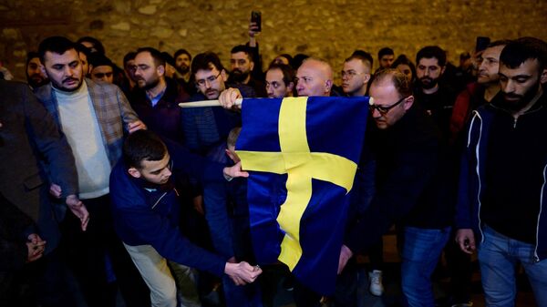 Manifestantes queimam a bandeira da Suécia em frente ao consulado geral da Suécia em Istambul depois que Rasmus Paludan, líder do partido político de extrema-direita dinamarquês Steam Kurs (Linha Dura), que também tem cidadania sueca, queimou uma cópia do Alcorão perto da embaixada da Turquia em Estocolmo, 21 de janeiro de 2023 - Sputnik Brasil