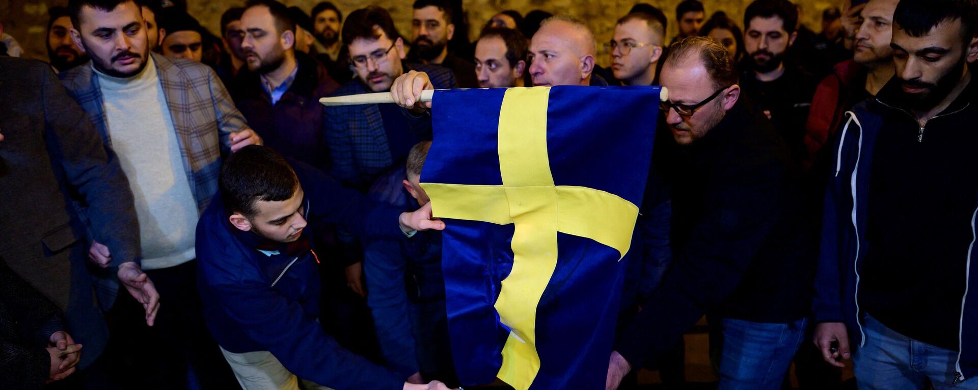 Manifestantes queimam a bandeira da Suécia em frente ao consulado geral da Suécia em Istambul depois que Rasmus Paludan, líder do partido político de extrema-direita dinamarquês Steam Kurs (Linha Dura), que também tem cidadania sueca, queimou uma cópia do Alcorão perto da embaixada da Turquia em Estocolmo, 21 de janeiro de 2023 - Sputnik Brasil, 1920, 27.01.2023