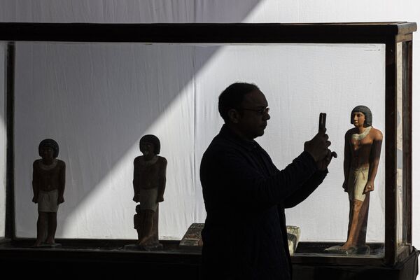 Um homem tira fotos perto das estátuas do faraó durante coletiva de imprensa na necrópole de Saqqara, ao sul de Cairo, onde foram descobertos uma múmia decorada com ouro e quatro túmulos, incluindo o &quot;guardião dos segredos&quot; de um antigo rei. - Sputnik Brasil