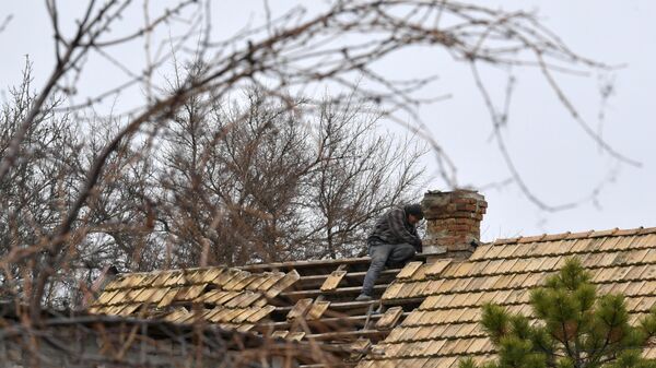 Morador reparando telhado de sua casa perto da cidade de Vasilievka após ataque das Forças Armadas da Ucrânia, foto publicada em 24 de janeiro de 2023. - Sputnik Brasil
