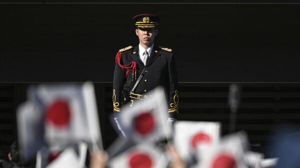 Simpatizantes agitam bandeiras na frente de guarda de membros da família real do Japão durante a tradicional cerimônia de saudação de ano-novo no Palácio Imperial, em Tóquio. Japão, 2 de janeiro de 2023 - Sputnik Brasil