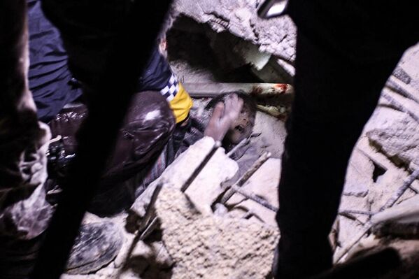 Socorristas tentam libertar um menino dos escombros de um prédio desmoronado após o terremoto na cidade síria de Azaz, na província de Aleppo, na madrugada de 6 de fevereiro de 2023. - Sputnik Brasil