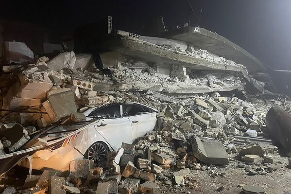 Carro sob os destroços de um prédio que desmoronou, na cidade de Azmarin, na província de Idlib, norte da Síria. - Sputnik Brasil