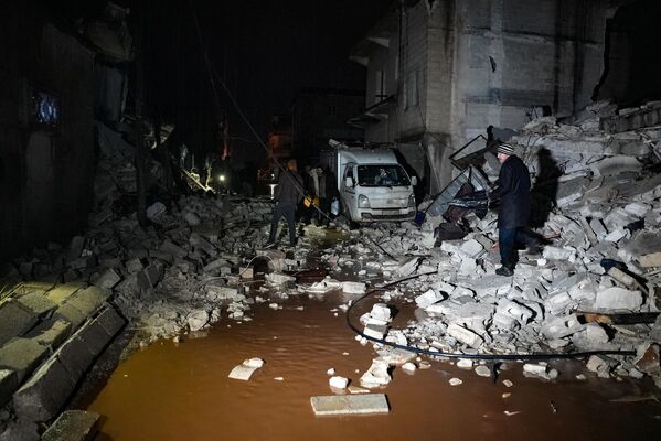 Moradores caminham entre escombros de edifícios desmoronados após um terremoto ter provocado destruição na cidade de Jandaris, distrito de Afrin, no noroeste da Síria. - Sputnik Brasil
