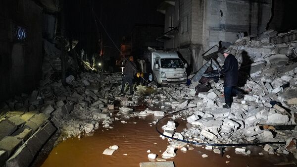 Moradores caminham entre escombros de edifícios desmoronados após um terremoto ter provocado destruição na cidade de Jandaris, distrito de Afrin, no noroeste da Síria - Sputnik Brasil