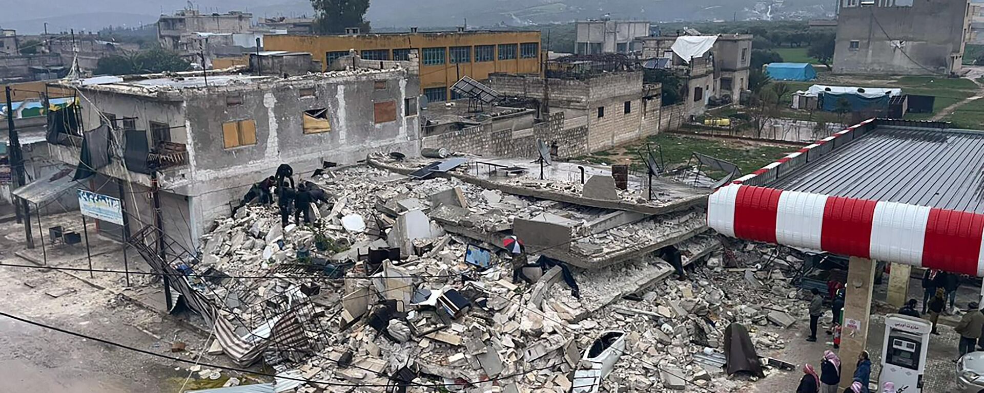 Pessoas vasculham os destroços de um prédio que desmoronou na cidade de Azmarin, na província síria de Idlib, no norte do país - Sputnik Brasil, 1920, 24.02.2023