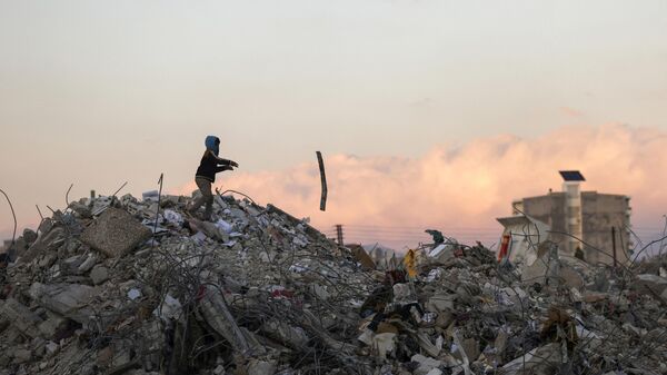 Menino sírio procura nos destroços por itens após terremoto devastador, em Jableh, província de Latakia, Síria, 10 de fevereiro de 2023 - Sputnik Brasil