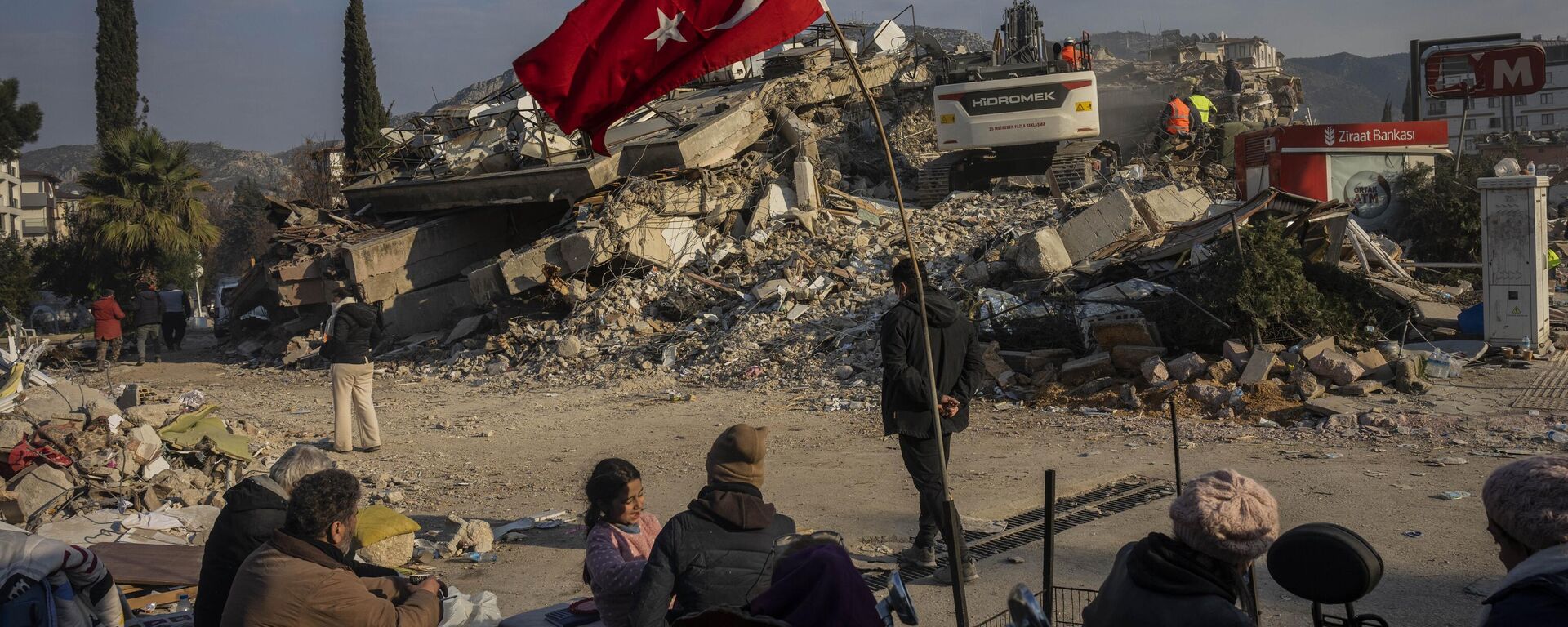Família sentada junto de prédio colapsado após terremoto, em Antália, Turquia, 11 de fevereiro de 2023 - Sputnik Brasil, 1920, 11.02.2023