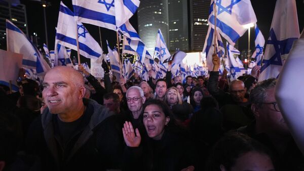 Israelenses agitam a bandeira nacional durante um protesto contra os planos do novo governo do primeiro-ministro Benjamin Netanyahu de reformar o sistema judicial - Sputnik Brasil