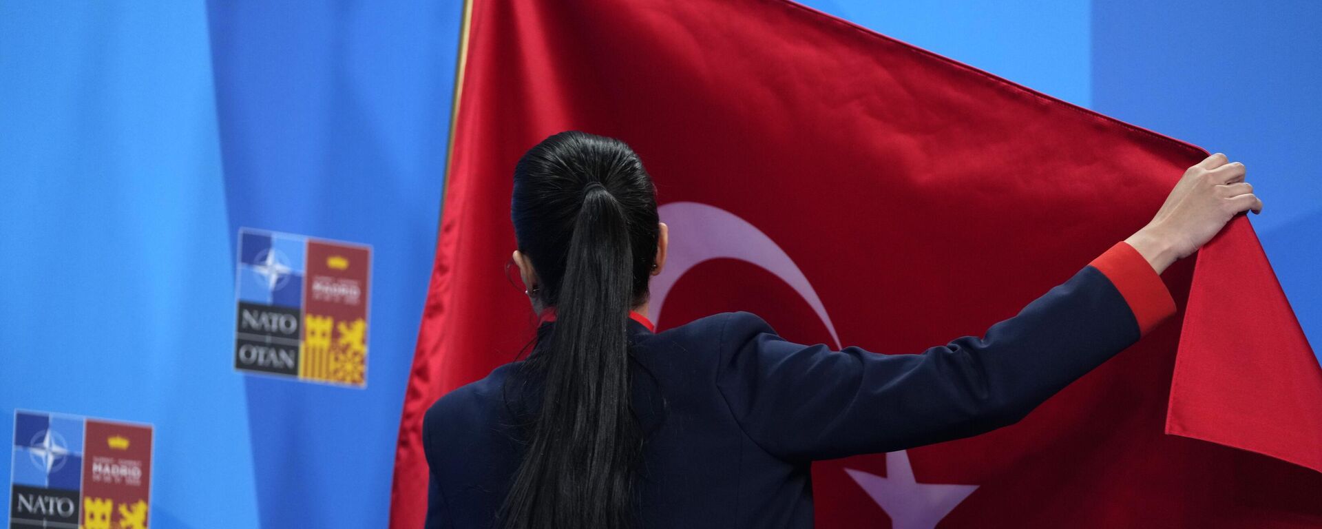Um membro da delegação turca ajusta a bandeira antes de um discurso do presidente turco Recep Tayyip Erdogan em uma cúpula da OTAN em Madri, Espanha - Sputnik Brasil, 1920, 06.03.2023