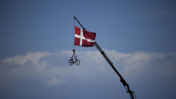 Bandeira dinamarquesa hasteada e uma bicicleta está suspensa de um guindaste enquanto os ciclistas passam durante a segunda etapa da corrida de bicicleta Tour de France, no sábado, 2 de julho de 2022. - Sputnik Brasil