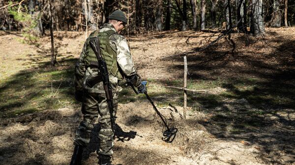Militar da Rússia com detector de metais durante exumação de restos de efetivos da República Popular de Lugansk fuzilados pelas Forças Armadas da Ucrânia, em Severodonetsk, foto publicada em 16 de março de 2023 - Sputnik Brasil