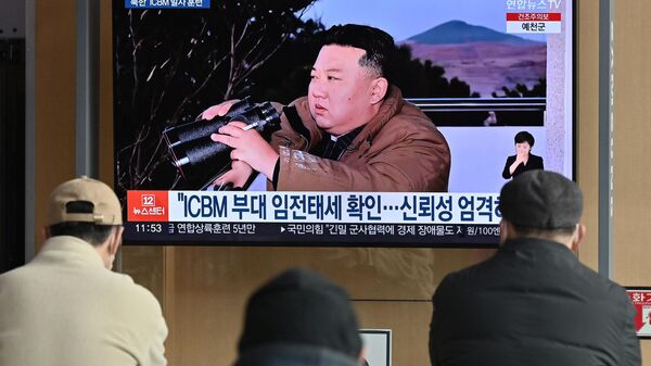 Pessoas assistem a um noticiário de televisão mostrando uma foto do líder da Coreia do Norte, Kim Jong Un, testemunhando o recente teste de disparo de um míssil balístico intercontinental Hwasong-17 (ICBM), em uma estação ferroviária em Seul, em 17 de março de 2023 - Sputnik Brasil