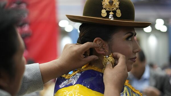 Uma mulher coloca brincos de ouro em um competidor Chola, se prepara para uma competição local para eleger os três principais personagens do carnaval - Chuta, Pepino e Chola - em La Paz, Bolívia 10 de fevereiro de 2023 - Sputnik Brasil