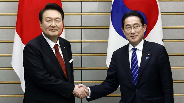 O presidente sul-coreano Yoon Suk Yeol, à esquerda, e o primeiro-ministro japonês Fumio Kishida apertam as mãos antes de sua reunião bilateral no gabinete do primeiro-ministro em Tóquio, 16 de março de 2023 - Sputnik Brasil
