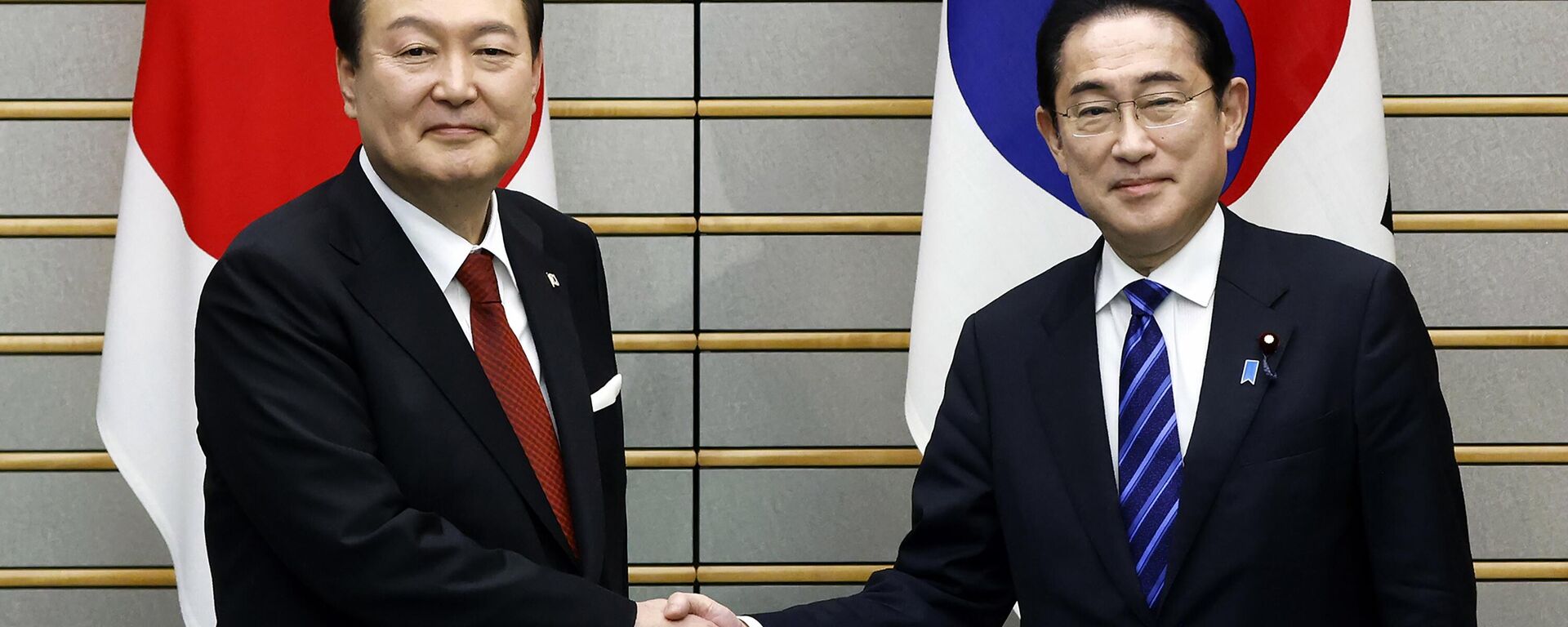 O presidente sul-coreano Yoon Suk Yeol, à esquerda, e o primeiro-ministro japonês Fumio Kishida apertam as mãos antes de sua reunião bilateral no gabinete do primeiro-ministro em Tóquio, 16 de março de 2023 - Sputnik Brasil, 1920, 06.05.2023