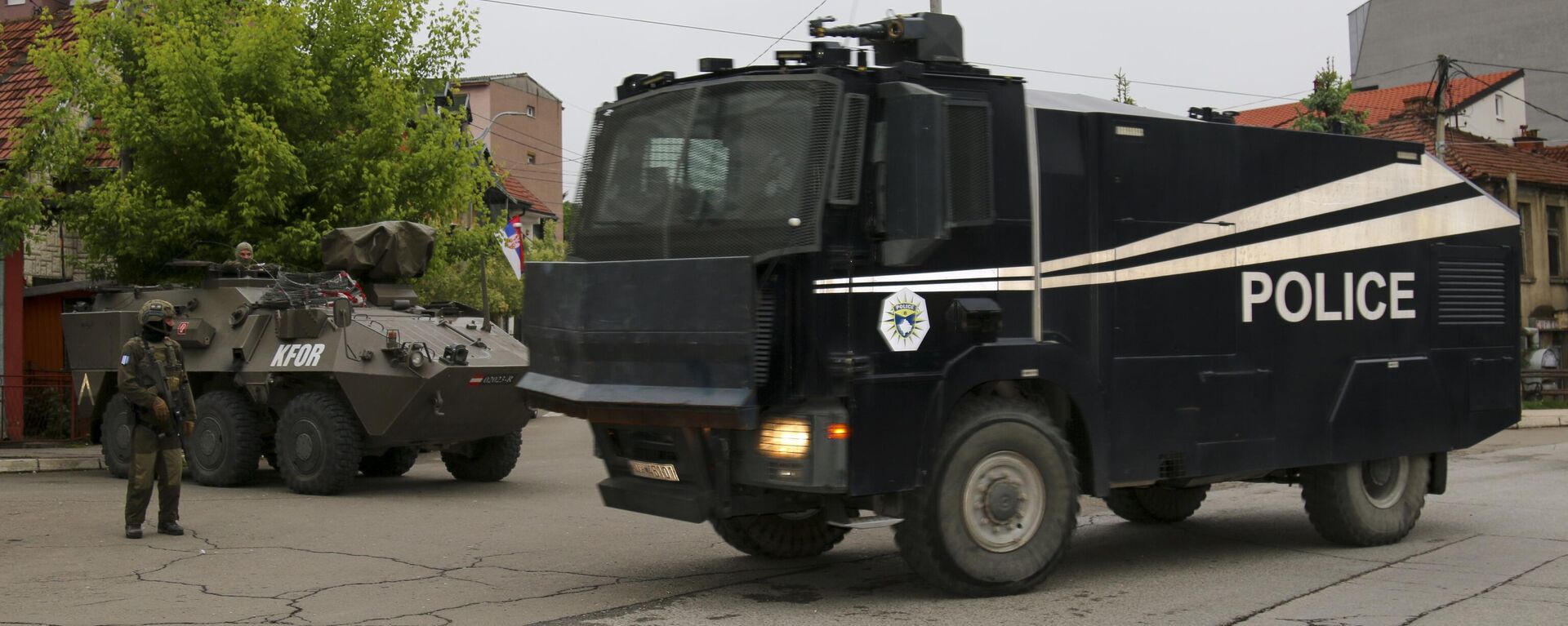 Caminhão de canhão de água da polícia de Kosovo passa enquanto soldados austríacos que servem na missão da OTAN em Kosovo, Força do Kosovo (KFOR, na sigla em inglês), vigiam uma rua na cidade de Zvecan, norte de Kosovo, 1º de junho de 2023 - Sputnik Brasil, 1920, 03.06.2023