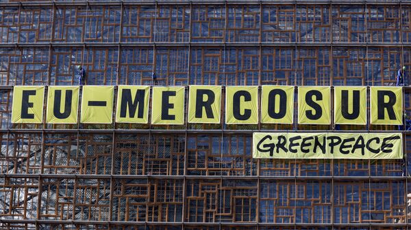 Ativistas da ONG ambiental Greenpeace penduram cartaz gigante no prédio do Conselho Europeu durante protesto contra o acordo União Europeia-Mercosul, fora de uma reunião de ministros do comércio do bloco europeu em Bruxelas, Bélgica, 25 de maio de 2023 - Sputnik Brasil