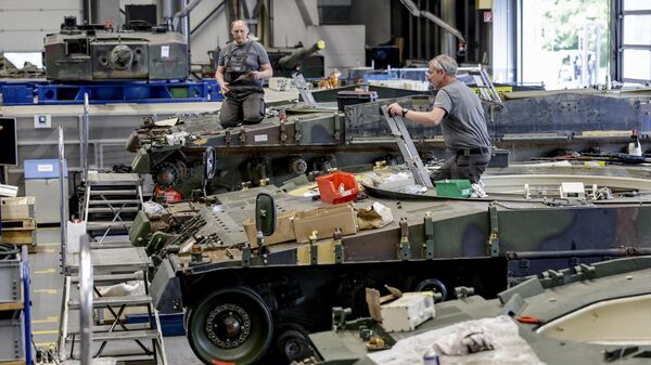 Trabalhadores mantêm e inspecionam um veículo de combate de infantaria alemão Puma — IFV Schuetzenpanzer (SPz) — e tanques de batalha Leopard 2A4 nas instalações da empresa alemã de armamentos e fornecedor automotivo Rheinmetall em Unterluess, norte da Alemanha, 6 de junho de 2023 - Sputnik Brasil
