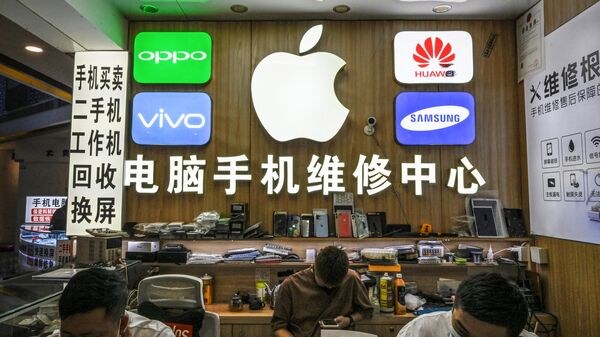 Funcionários trabalhando em uma loja com logotipos de fabricantes de smartphones, incluindo Apple, Huawei, Oppo, Vivo e Samsung, no mercado de eletrônicos Huaqiangbei, em Shenzhen, China, 12 de julho de 2022 - Sputnik Brasil