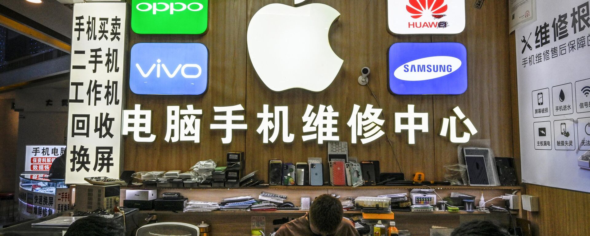 Funcionários trabalhando em uma loja com logotipos de fabricantes de smartphones, incluindo Apple, Huawei, Oppo, Vivo e Samsung, no mercado de eletrônicos Huaqiangbei, em Shenzhen, China, 12 de julho de 2022 - Sputnik Brasil, 1920, 12.06.2023