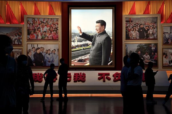 Pessoas em frente de imagens do presidente chinês Xi Jinping no museu do Partido Comunista da China em Pequim. - Sputnik Brasil