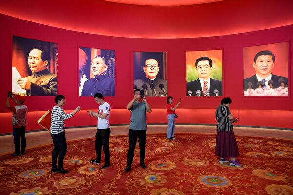 Grupo de pessoas tira fotos na frente de retratos de líderes chineses. - Sputnik Brasil