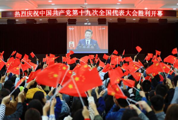 Estudantes universitários agitam bandeiras nacionais enquanto assistem ao discurso de abertura de Xi Jinping no 19º Congresso do Partido Comunista em Huaibei. - Sputnik Brasil